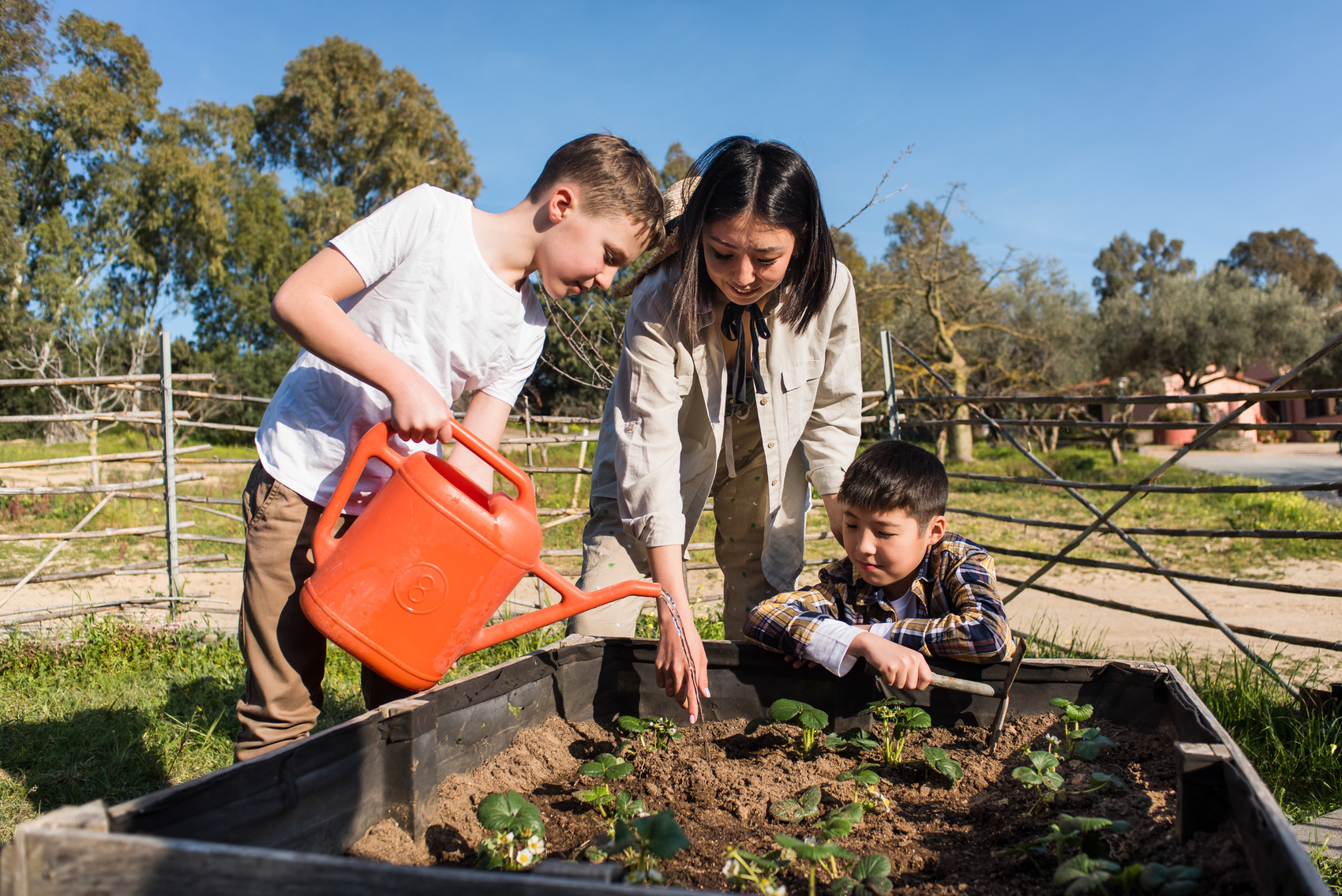 Woman Pointing Where to Sprinkle Water to a Boy Outdoors